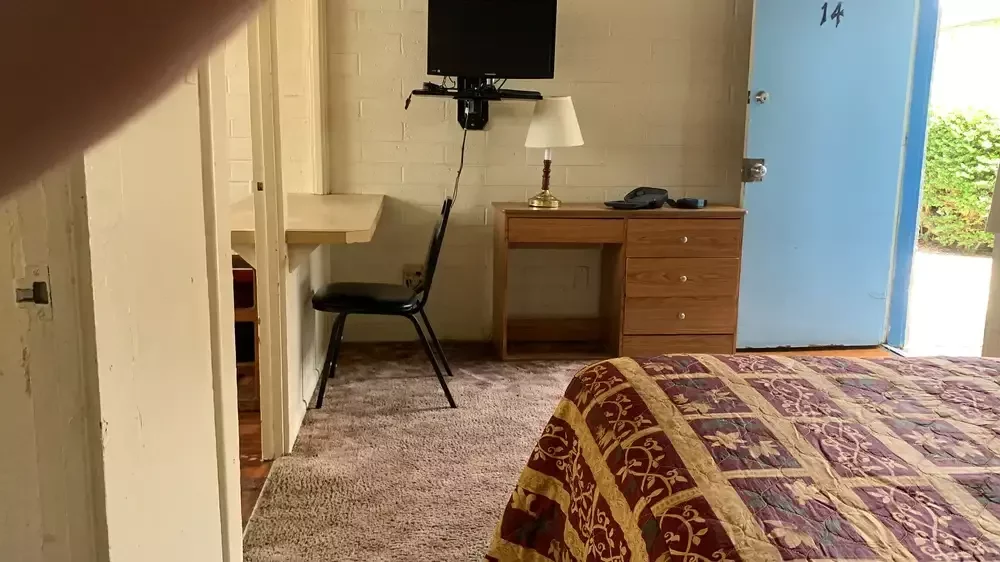 Before: a motel room with a patterned bedspread, old carpet and a wall-mounted TV.