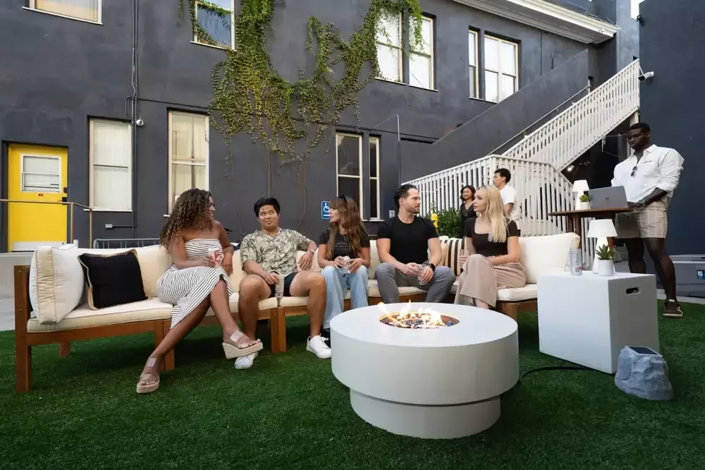 Guests relaxing on lounge sofas around a fire table in the Neon Elm courtyard.