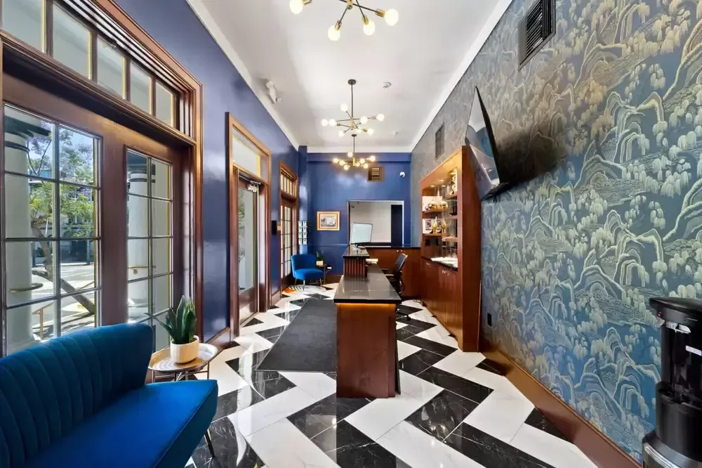 The Neon Elm lobby with navy walls, gold wave wallpaper, a check-in bar and black-and-white chevron floor.